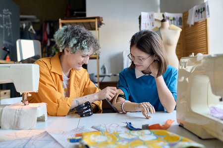 Portrait of two girls with disability looking at each others prosthetics and having fun in...