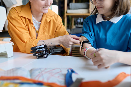 Close up of two girls with disability inspecting each others prosthetics in school class copy spaceの写真素材