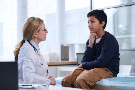 Side view portrait of young Middle Eastern boy talking to female doctor in pediatric clinicの写真素材