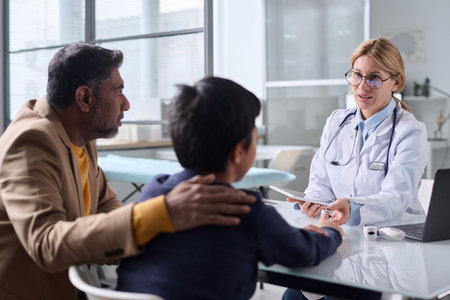 Portrait of caring female doctor consulting Middle Eastern family of father and son in clinicの写真素材