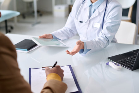 Close up of unrecognizable Middle Eastern man signing patients card on clipboard during consultation in medical clinic copy spaceの写真素材