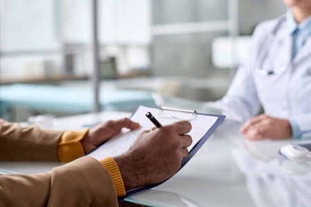 Close up of unrecognizable man holding clipboard in clinic and writing medical information copy spaceの写真素材