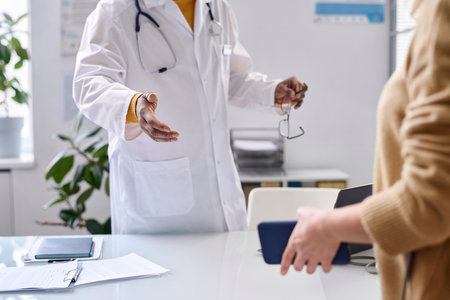 Close up of unrecognizable doctor greeting patient in medical clinic and gesturing for seat copy spaceの写真素材
