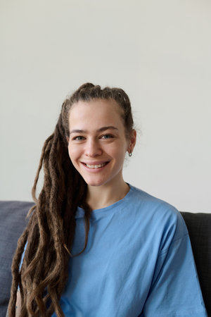 Minimal portrait of young Caucasian woman with long dreadlocks smiling at cameraの写真素材