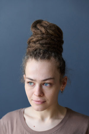 Vertical close up of Caucasian woman with dreadlocks in bun hairstyle and no makeup looking away on...
