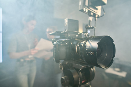 Background image of professional digital video camera on stand in video production studio with smoke effect copy spaceの写真素材