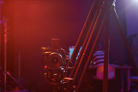 Front view background image of pro digital camera set up on rig in studio with red neon lights copy...