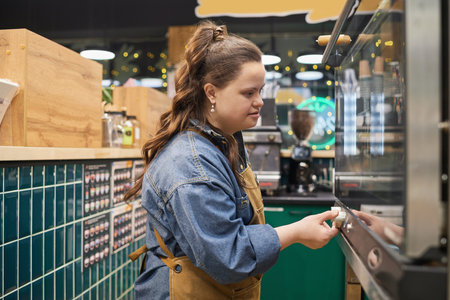Side view portrait of independent adult woman with Down syndrome working with oven in cafe or bakeryの写真素材
