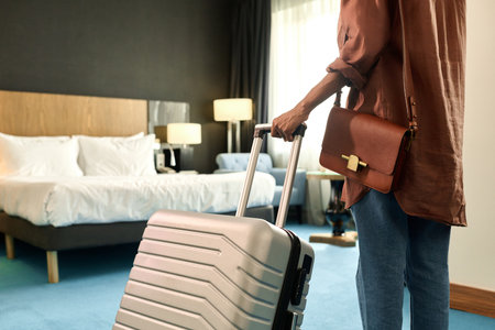 Cropped back view of African American woman entering hotel room and holding suitcase copy spaceの写真素材