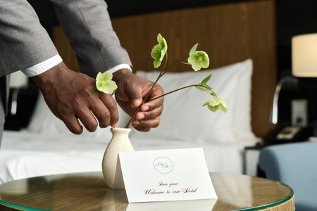 Close up of Welcome note in luxury hotel with male hands arranging flower decor copy space