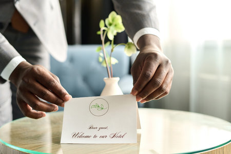 Close up of male hands carefully arranging welcome note for guest in luxury hotel copy space