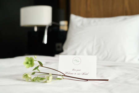 Background image of welcome note with delicate flower decor on bed in luxury in hotel room copy spaceの写真素材