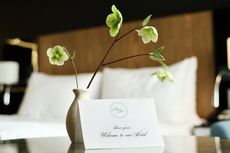 Close up background image of delicate floral decor in hotel room with welcome note on table copy spaceの写真素材