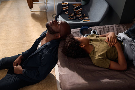 High angle of African American father and son comforting each other touching hands in sunlight copy spaceの写真素材