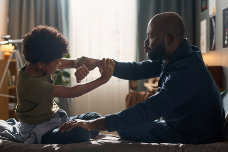 Side view portrait of African American father trying to calm down teenage son and holding his arms in hysterical fightの写真素材