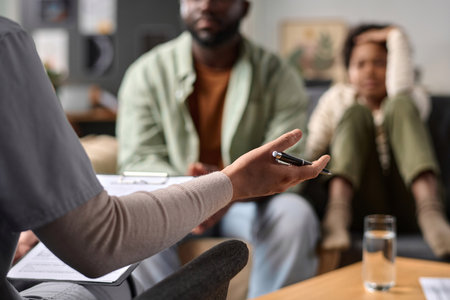 Close up of female therapist gesturing and talking to father and son in family support session focus on hand holding pen copy spaceの写真素材