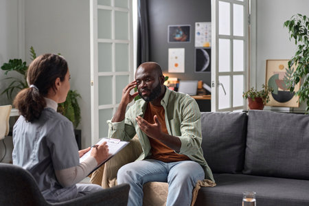 Portrait of adult African American man talking to psychotherapist in one on one session copy spaceの写真素材