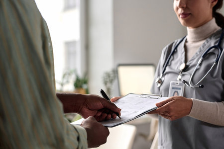 Close up of unrecognizable man signing medical form on clipboard in clinic copy spaceの写真素材