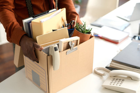 Close up of unrecognizable Black man holding box with personal items in office packing for leave or retirement copy spaceの写真素材