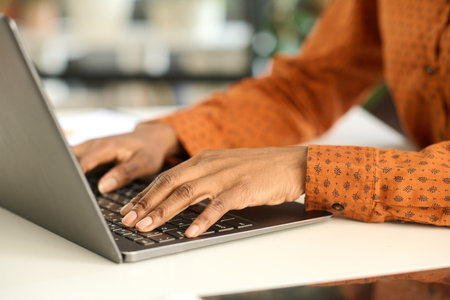 Close up of unrecognizable Black young woman typing on laptop keyboard with focus on female hands copy spaceの写真素材