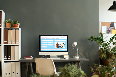 Minimal background image of job hunting website on computer screen at home office workplace against grey wall, copy spaceの写真素材