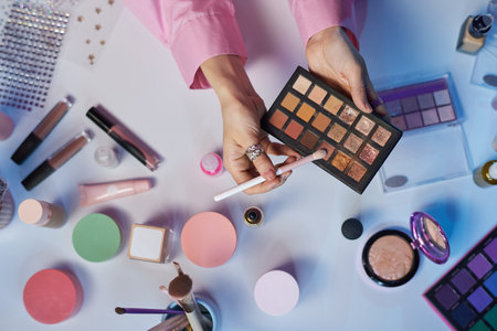 Top view unrecognizable woman as beauty influencer testing make up palette with glittering eyeshadow over table and recording tutorial copy spaceの写真素材