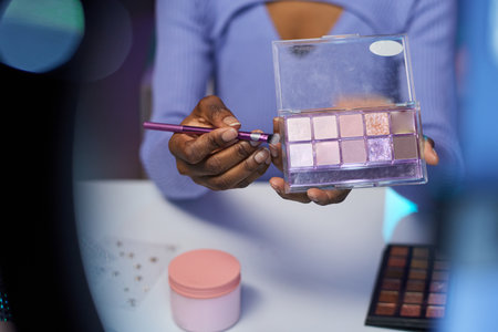 Closeup of unrecognizable African American girl testing make up palette with glittering eyeshadow over table and recording tutorial copy spaceの写真素材