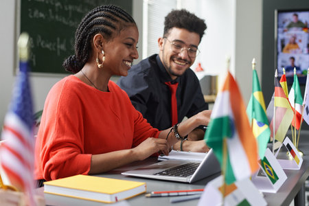 Two young students man and woman working on project together in multicultural school classroom, copy spaceの写真素材