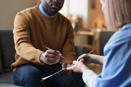 Close up of adult Black man signing form on clipboard for at home medical services during nurse visit copy spaceの写真素材