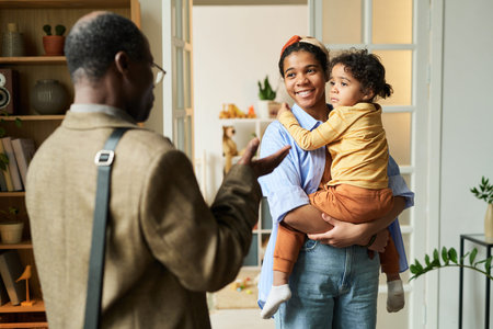 Joyful reunion of a parent and child in a cozy living room. Parent holding child while other person...