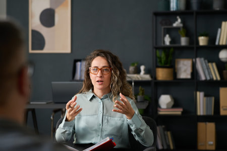 Female professional explaining ideas during a discussion in well-organized office space. Engaging in detailed conversation with a personの写真素材
