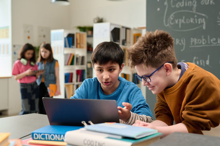 Portrait of two young boys using computer together in colorful school library setting and looking at...