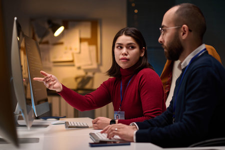 Portrait of computer development team discussing project in office with young woman pointing at...