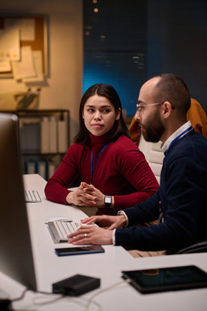 Vertical portrait of software development team collaborating in office with young woman looking at...