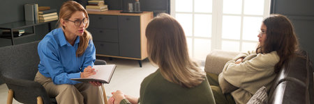 Header image of female therapist consulting mother and daughter fighting during family counseling sessionの写真素材