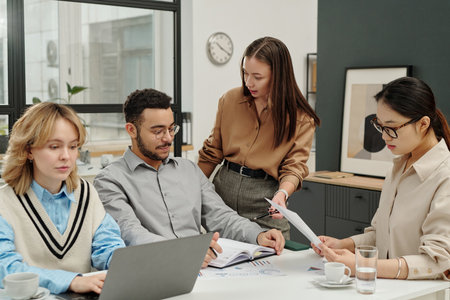 Portrait of young businesswoman as female boss giving instructions team of colleagues during business meeting in officeの写真素材
