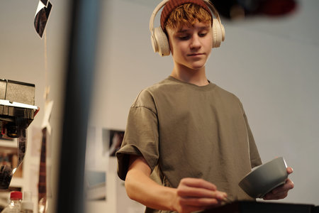 Low angle shot of teenage boy wearing headphones while working with photography in darkroom, copy...