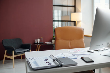 Minimal office interior with sleek design and leather chair at workplace table with computer, copy spaceの写真素材