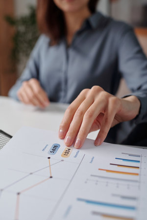 Vertical closeup of female hand taking documents with data report while working at desk in office copy spaceの写真素材