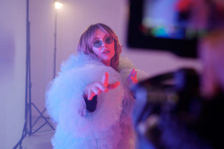 Waist up portrait of actress performing to camera while wearing oversized costume and sunglasses...