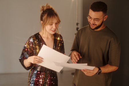 Medium closeup of woman and director reading script notes and discussing scene details backstage during studio shootの写真素材