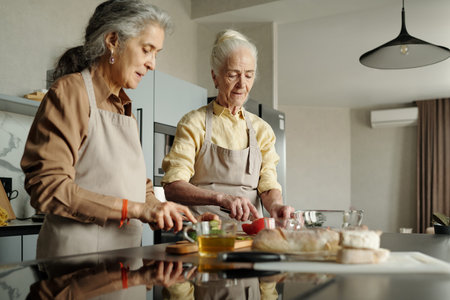 Elderly man and woman preparing meal in modern kitchen with focused attention, cutting vegetables...