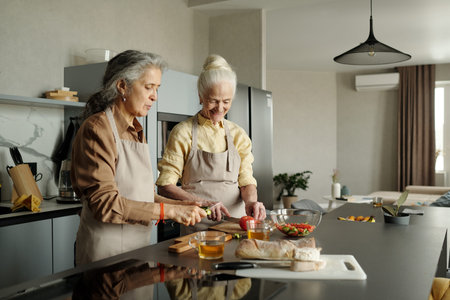 Senior women preparing a healthy meal together in a modern kitchen with various fresh ingredients...