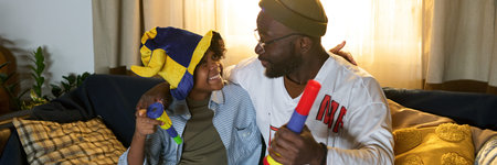 African American father spending quality time with his son while smiling and bonding in cozy living...