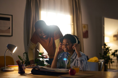 Pleasant evening study session with family helping under warm indoor lighting, creating productive yet relaxed atmosphere with snacks and educational materials present aroundの写真素材