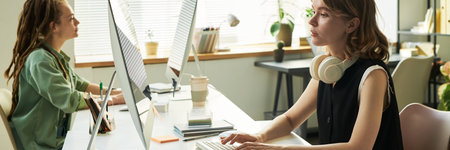 Young adult Caucasian woman working on computer sitting at desk in modern officeの写真素材