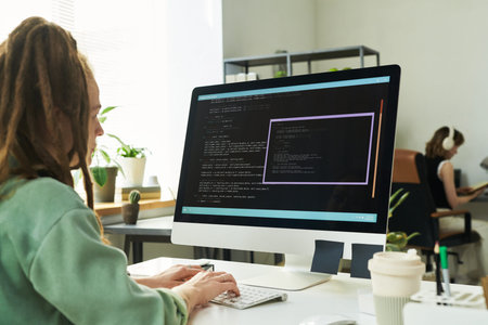 Caucasian young adult woman with dreadlocks developing neural network code on desktop computer in...
