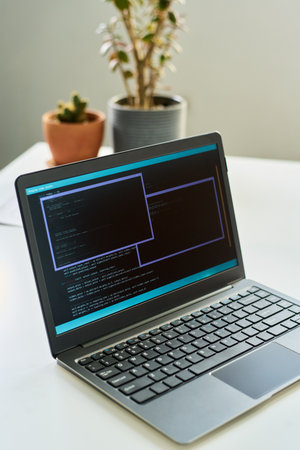 Open laptop displaying neural network development code on screen positioned on desk with blurred potted plants in background, focusing on artificial intelligence programming processの写真素材