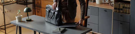 Man standing at desk preparing for therapy session by placing laptop and briefcase on tabletop, modern office setting with organized shelves in backgroundの写真素材
