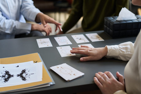 Middle aged woman conducting psychological assessment using inkblot test cards and diagrams on desk...